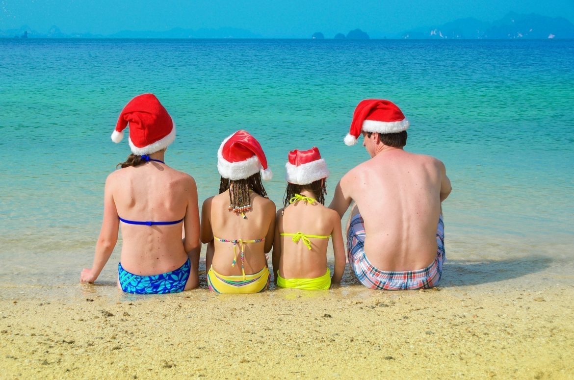 Family in santa hats having fun on beach vacation, new year and christmas holiday concept